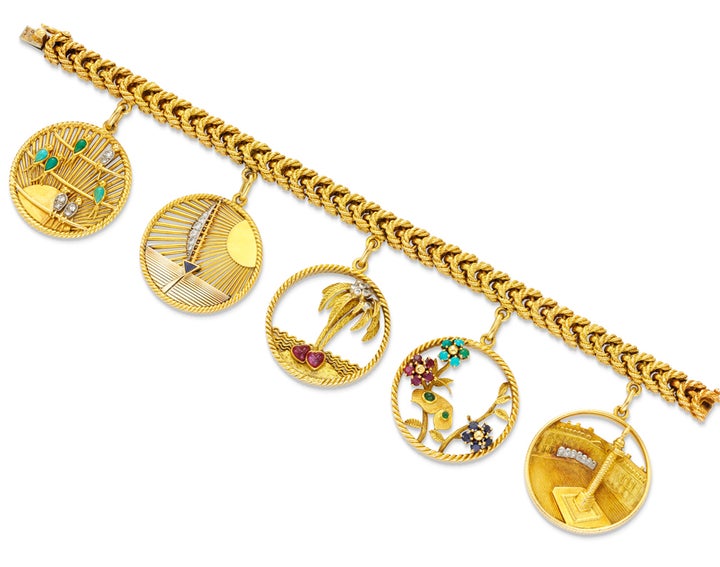 Simon Teakle’s Van Cleef & Arpels’ 18K gold and gem set charm bracelet with link bracelet suspending five large circular gem set charms depicting birds, a yacht, a palm tree, flora and the Place Vendome. Bracelet and each charm signed and numbered. Paris, circa 1965. 