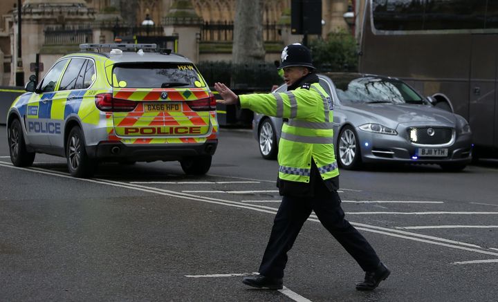 A police officer stops traffic as the Jaguar car of British Prime Minister Theresa May is driven away from Parliament