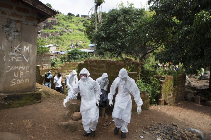 A burial team wearing protective clothing remove the body of a person suspected of having died of Ebola in Freetown, Sierra Leone, on Sept. 28, 2014.