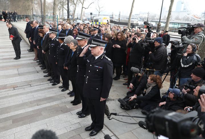Police officers salute during a minute's silence outside New Scotland Yard on Thursday morning