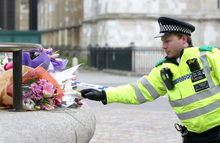 A police officer rearranges floral tributes to those killed in the attack