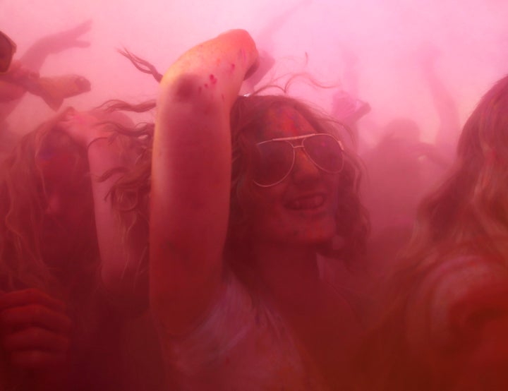 Participants dance and throw colored chalk during the Holi Festival of Colors at the Sri Sri Radha Krishna Temple in Spanish