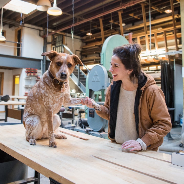 Natalie Shook gives Bones, her Australian Cattle dog, a pawshake at her workshop.