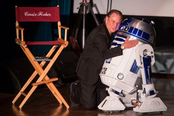 Todd Fisher hugs an R2-D2 robot near an empty chair for his late sister, actress Carrie Fisher, during a joint public memoria