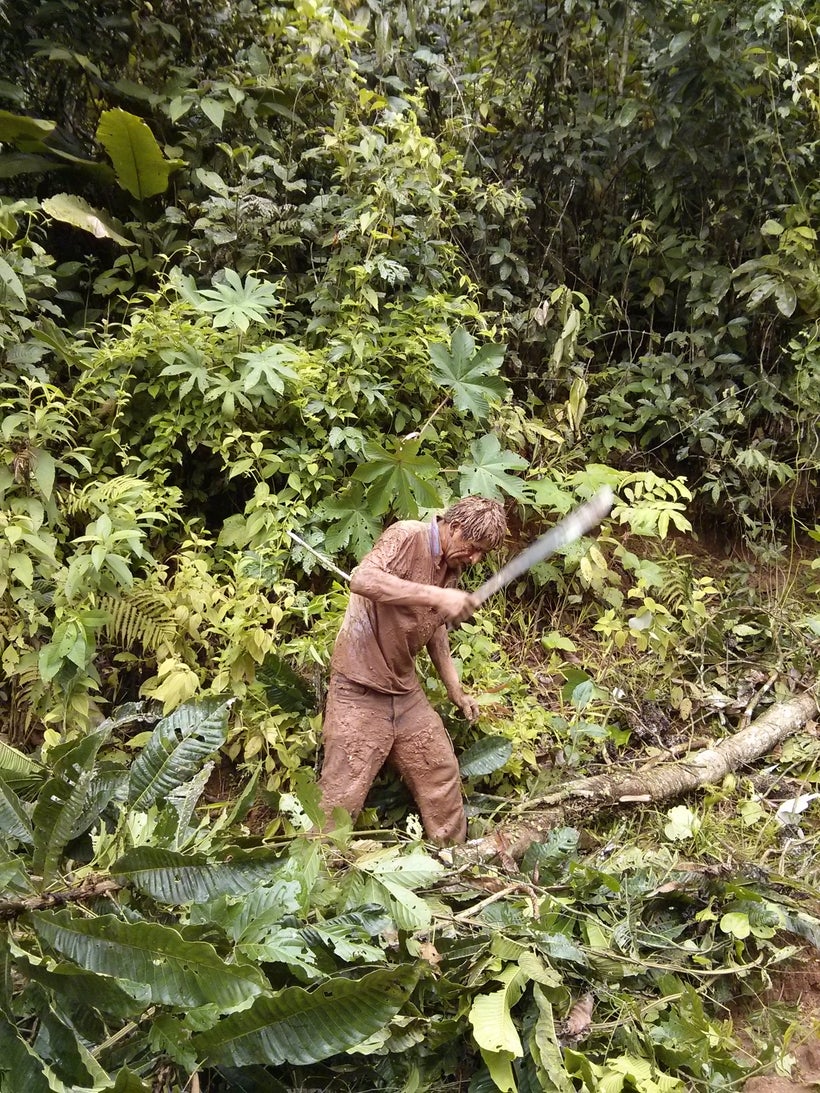 Man cutting tree trunks to help people hold on to them in the river’s rising water.
