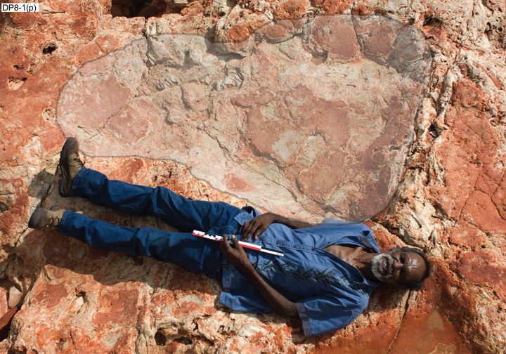 Richard Hunter is seen lying next to the dinosaur print, which measures 5 feet 7 inches.