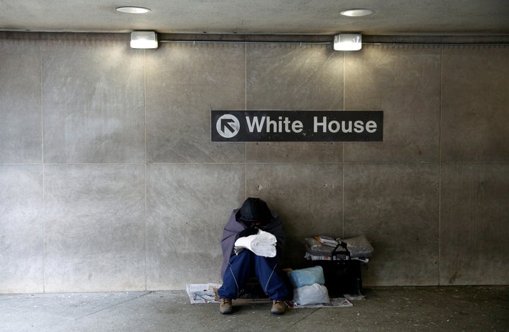 On an unseasonably cold day, a homeless person tries to stay warm at the entrance of a subway station near the White House in