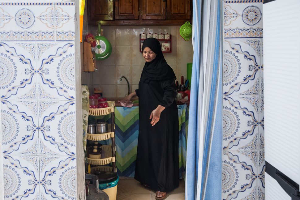 Naziha Bel Jayyed, the mother of a former fighter, washes dishes in her home in a suburb in northwest Tunis.