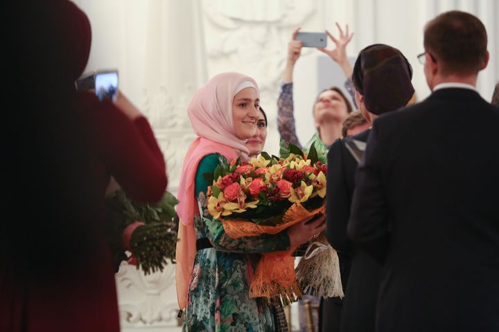 Firdaws designer Aishat Kadyrova accepts bouquets of flowers after runway presentation