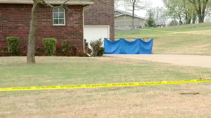 A blue tarp covers part of the scene of Monday's deadly shooting outside Broken Arrow, Oklahoma. Authorities said two of the suspects died in the home, while a third died in the driveway.