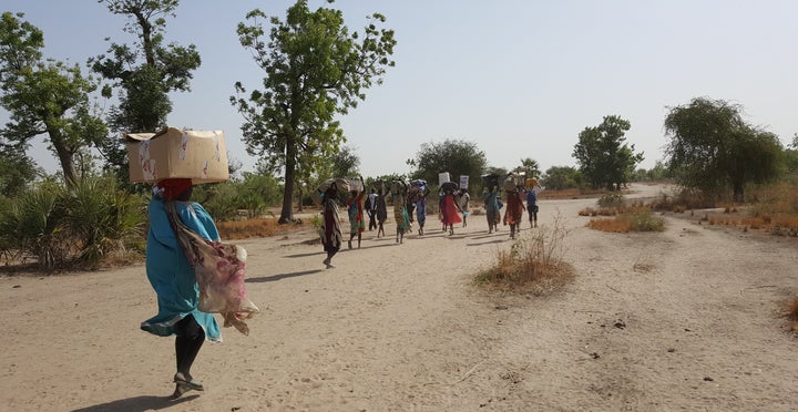 Mobile health workers in South Sudan sometimes have to walk for long hours, so they hire people from the local community to help them haul the supplies they can't carry on their backs.