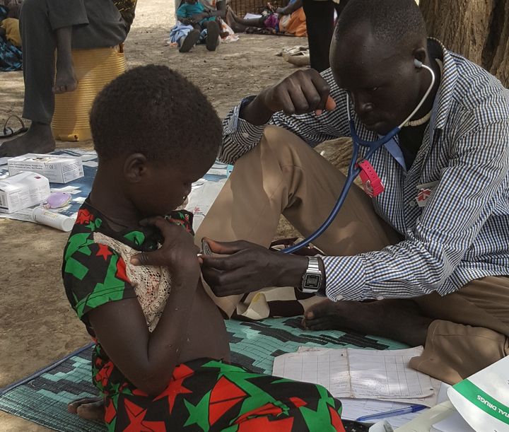 An MSF community health worker examines a 4-year-old girl suffering from malnutrition.