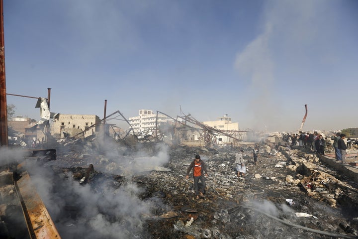 People walk on the rubble of an electronics warehouse store after a Saudi-led airstrike destroyed it in Yemen's capital of Sa