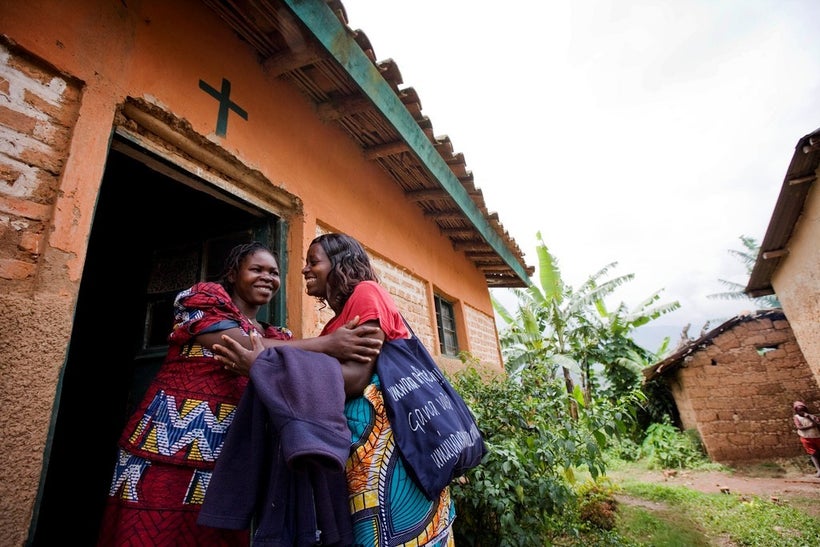 A community health worker greets a pregnant woman outsider her home in Rwanda.