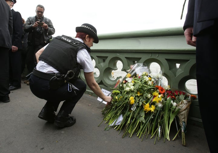 <strong>A police office lays flowers at a vigil held on Westminster Bridge in London.</strong>