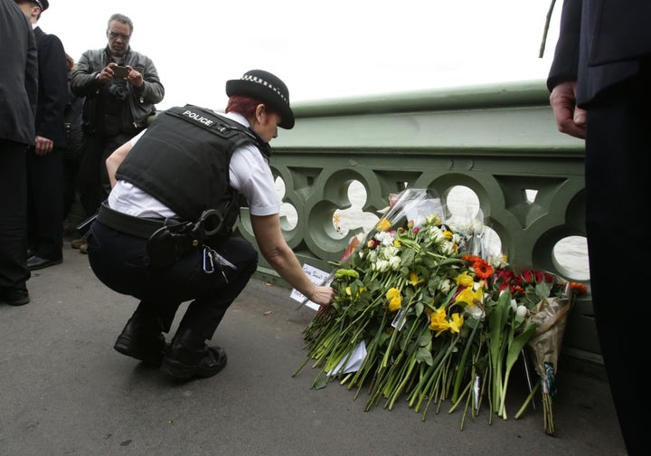 A police office lays flowers at a vigil held on Westminster Bridge in London.