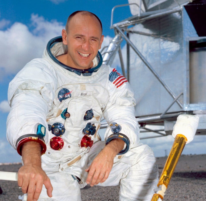 U.S. astronaut Alan Bean kneels in front of a lunar module in the NASA training center.