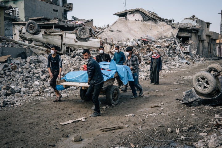 Local volunteers carry the bodies of civilians found in the rubble of a building in the Mosul al Jadidah neighborhood of Mosul.