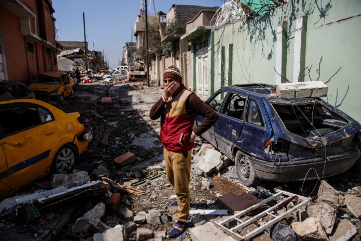 Neighbors cover their faces because of the smell of corpses in the Mosul al-Jadida neighborhood of Mosul.