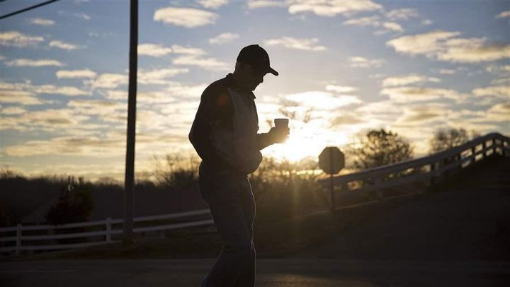 A man walks with a cup of coffee as the sun rises in Lula, Georgia. Georgia and many other states are considering a complex tax-credit program designed to promote economic development in rural areas.