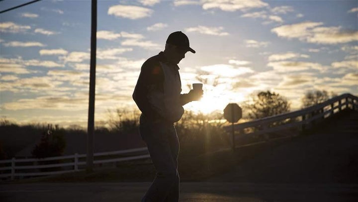 A man walks with a cup of coffee as the sun rises in Lula, Georgia. Georgia and many other states are considering a complex t