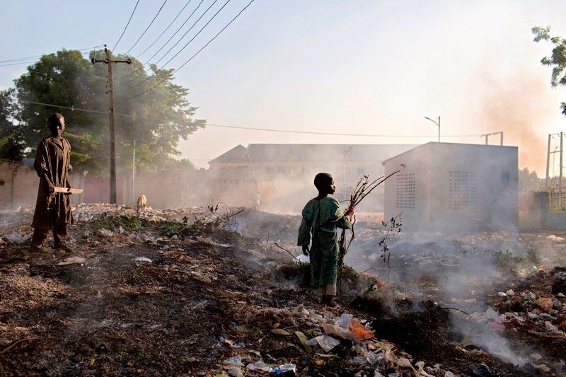 Young boys collect wood from a trash pile that is being burned in Maiduguri, Nigeria.