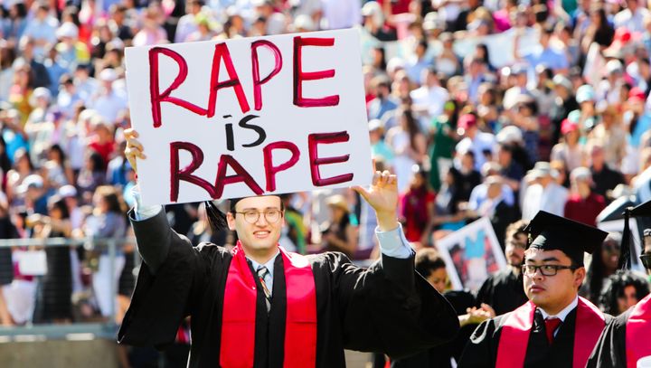 A Stanford student holds a sign reading "rape is rape" during 2016 graduation ceremonies. 