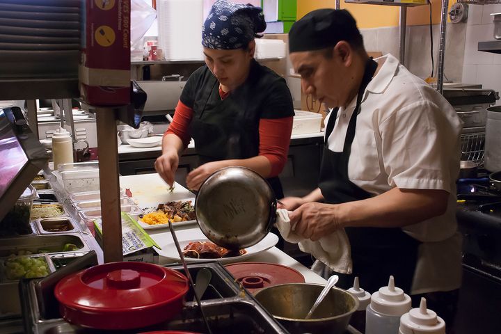 Miguel Ocorima adds mole to a main dish as a second 5 Rabanitos cook sprinkles cilantro onto a dish (Elizabeth Vlahos - Feb. 26, 2017).