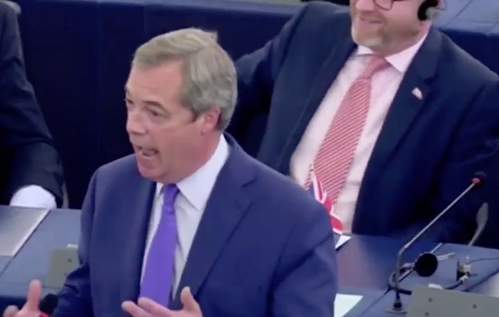 Paul Nuttall can be seen smirking over Farage's right shoulder