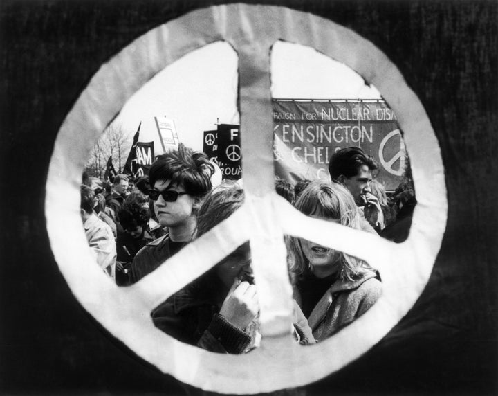 During a 1963 anti-nuclear demonstration from Aldermaston to London, a peace symbol frames the marchers and their banners.