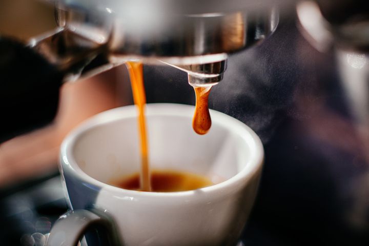 Espresso pours out of a machine.