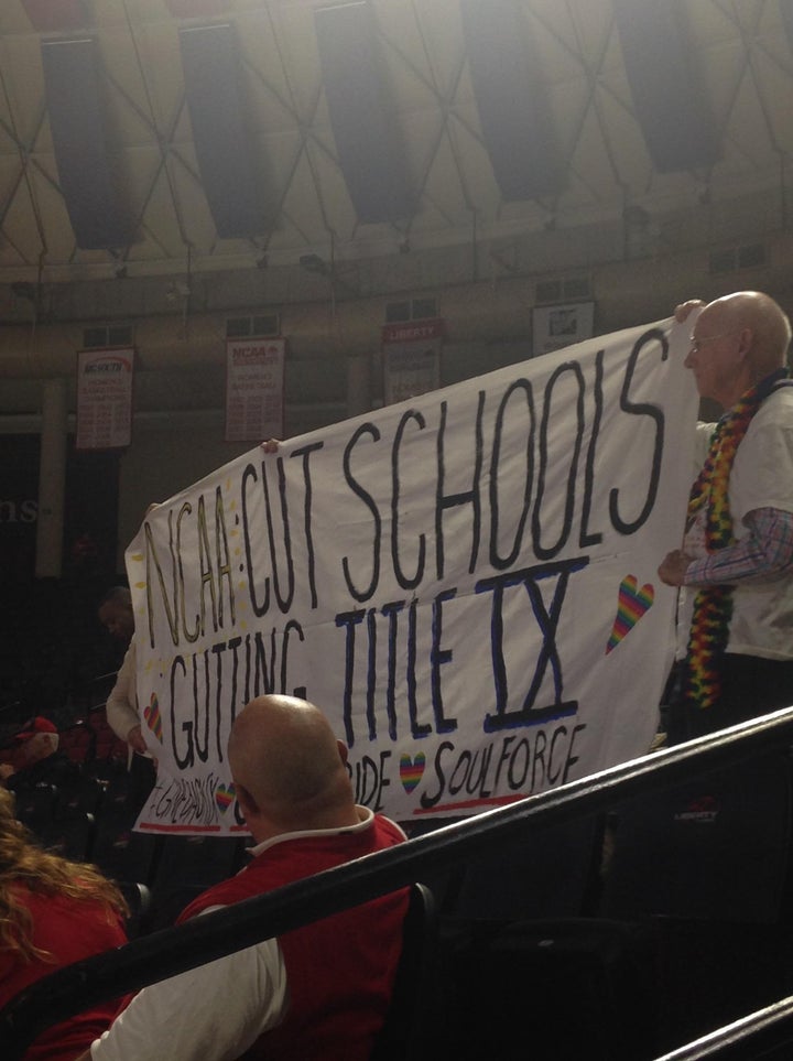 Soulforce activists hoist a banner at the Big South conference women’s basketball championships held at Liberty University, a