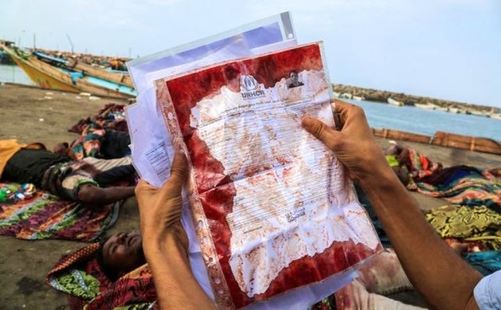 A man holds the UNHCR temporary registration document covered in blood from a refugee killed off the coast of Yemen on March 17, 2016.
