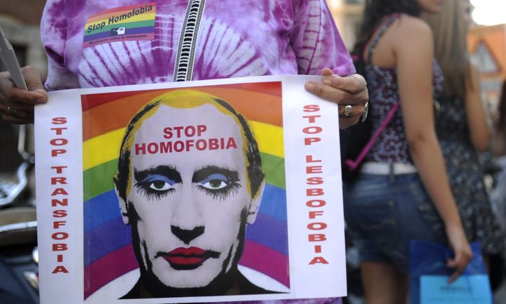 A demonstrator holds a poster depicting Russian President Vladimir Putin with makeup outside the Ministry of Foreign Affairs and Cooperation in Madrid on September 3, 2013.
