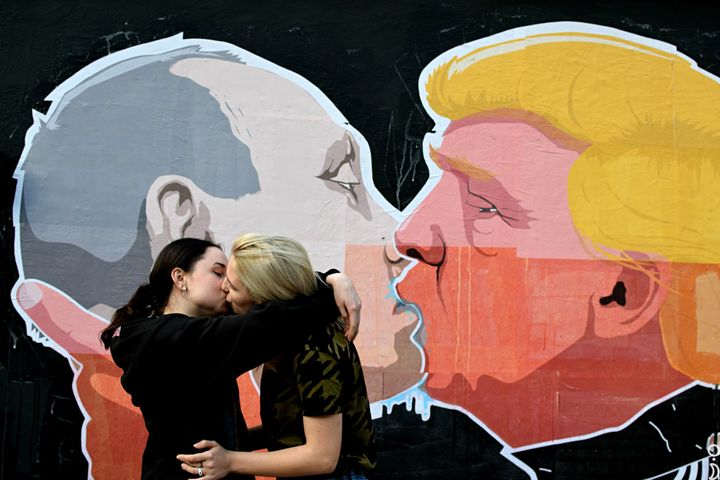 A lesbian couple kiss in front of a mural depicting Putin and Donald Trump locked in embrace in Vilnius, Lithuania, 2016