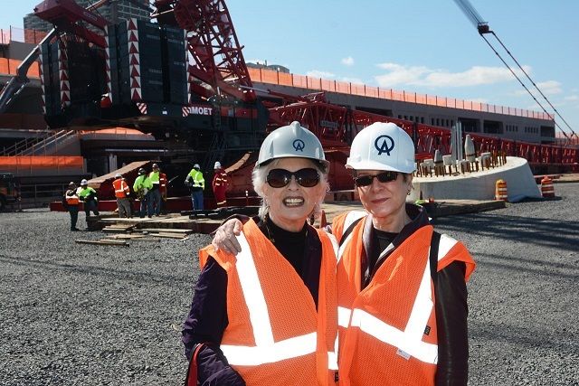 Roxie Munro and I are working on a book about the Wheel. (I’m on the left). The cab of the giant crane is where it says “MOET.” You’re looking at the back of the crane. The red, white and gray objects are ballast that hang from the short boom. The large boom is lying on the ground. On the right you can see a leg pedestal awaiting the lower leg The small brown extrusions are where the anchor bolts go. There are two conical “dowels”that fit into depressions in the leg. The pipes in the center are for electrical wires.