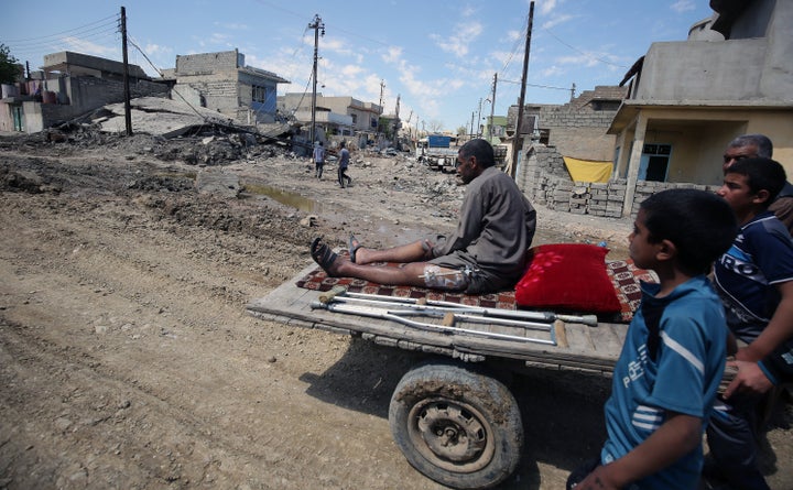 Iraqis help transport an injured man on a cart in the Maghreb neighbourhood in the western part of the northern city of Mosul on April 6, 2017.