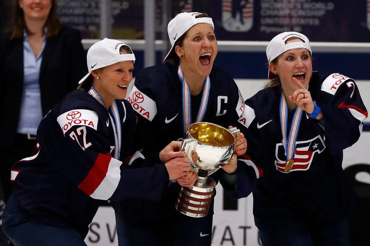 Kacey Bellamy, left, Meghan Duggan and Monique Lamoureux grab on to the championship trophy after beating Canada, 3-2, in overtime in the gold medal game in Plymouth, Michigan.