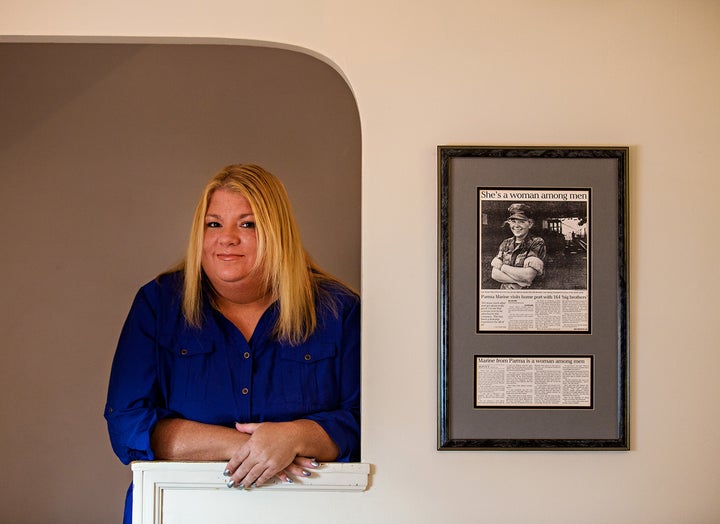 Marine veteran and homelessness advocate Rosie Palfy, who served in the Gulf War era as a combat correspondent, poses next to a framed newspaper article about her service. Credit: Scott Shaw Photo.