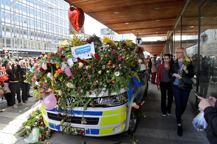 A police vehicle is seen adorned with a mound of flowers and balloons following Friday's attack.