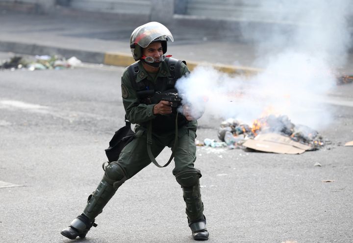 A riot police officer fires tear gas during the protest in Caracas. 
