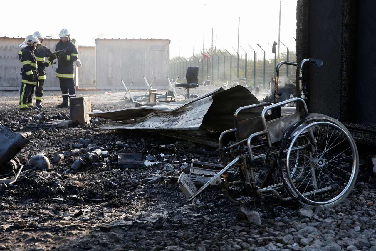 French firemen stand amid the ruins of the camp on Tuesday morning