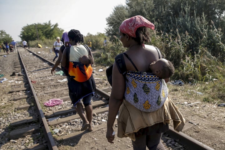Migrants, hoping to cross into Hungary, walk with babies on their backs along a railway track outside the village of Horgos i