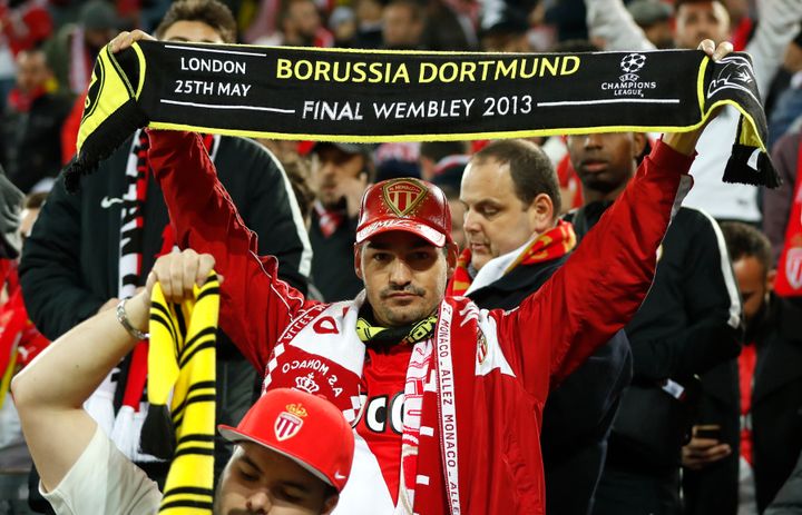Monaco supporters with Borussia scarves react in the stadium after the match was postponed
