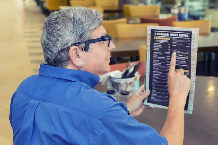 Person using OrCam’s MyEye to read a menu. 