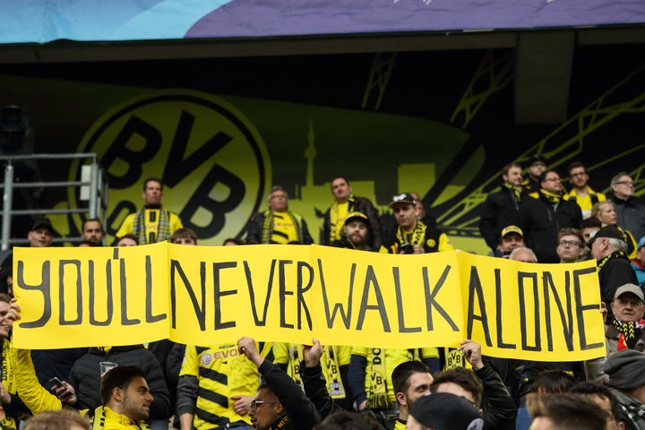 Fans of Borussia Dortmund hold up a banner saying You'll Never Walk Alone before the UEFA Champions League Quarter Final firs