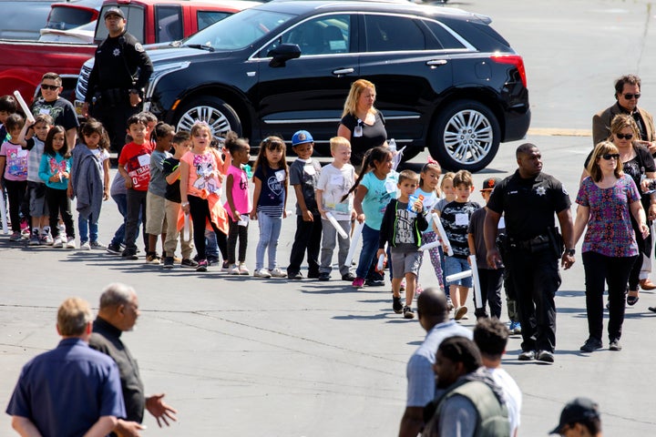 A San Bernardino Police Department officer leads children from North Park Elementary from school busses before being reunited with their families outside of Cajon High School after a shooting at North Park Elementary School on Monday, April 10, 2017 in San Bernardino, CA.