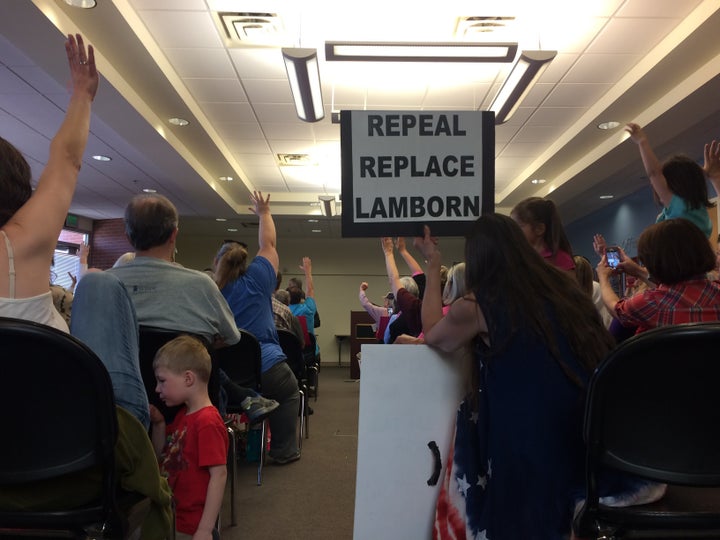 Audience members hold up their hands to ask Lamborn questions during a town hall event on Wednesday.