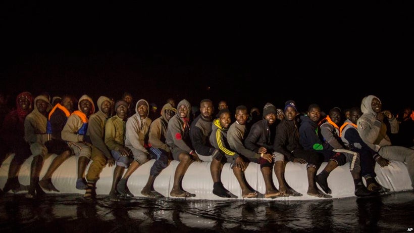 Refugees and migrants from many different African nationalities sit aboard an overcrowded rubber boat leaving Libyan territor