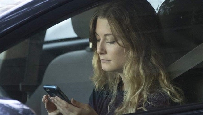 A California driver uses her phone while stopped in traffic in Sacramento. New data indicates risky driving behavior varies b